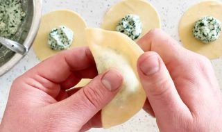 Folding a disc of pasta into a half moon shape.