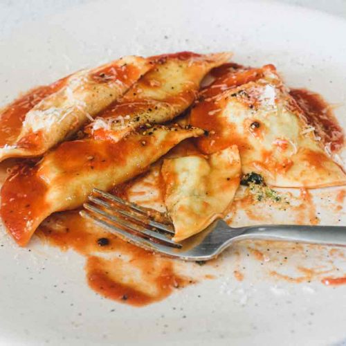 A bowl Mezzelune Pasta with Cavolo Nero & Ricotta with a fork.