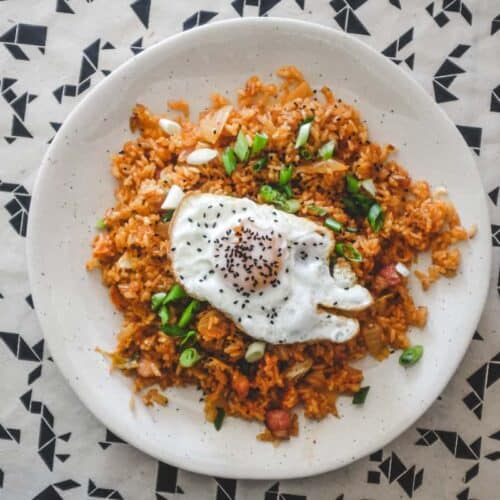 A plate of kimchi fried rice with a crisp fried egg on top scattered with spring onions