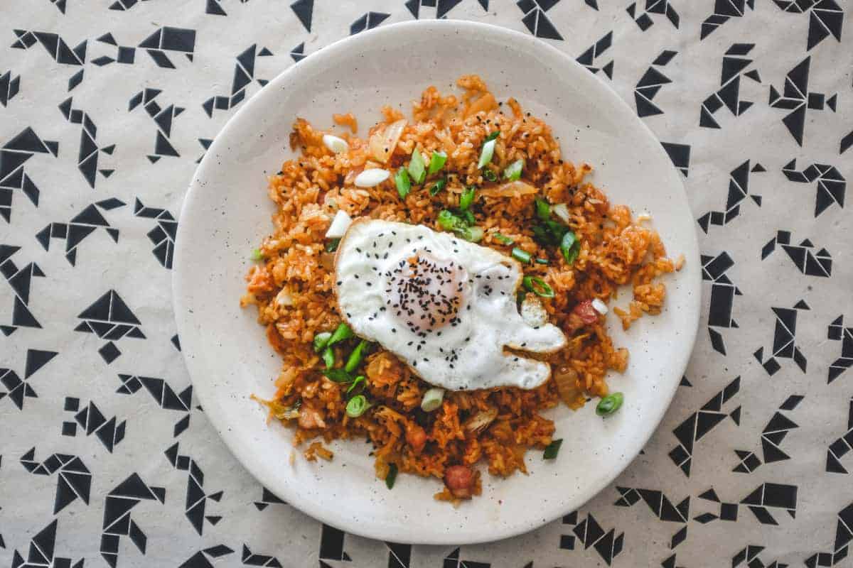 A plate of kimchi fried rice with a crisp fried egg on top scattered with spring onions