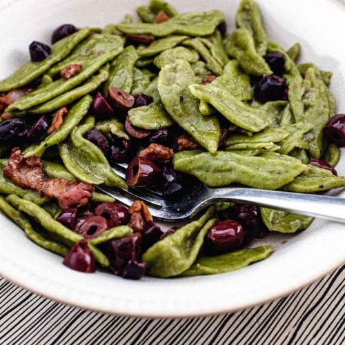 A bowl of foglie d'ulivo pasta with pancetta and black olives