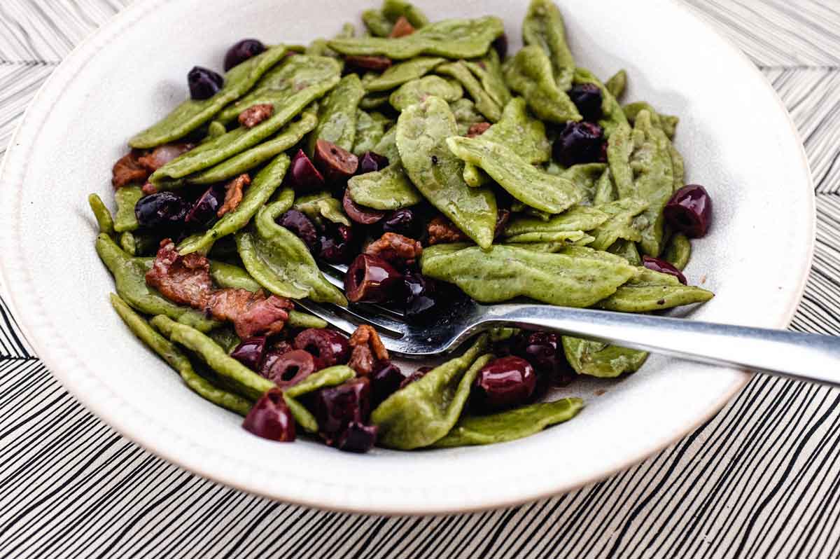 A bowl of foglie d'ulivo pasta with pancetta and black olives