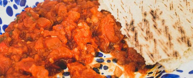 Moroccan Matbucha in a vibrant blue meze bowl. Peppers and tomatoes are stewed to a thick, tangy paste.