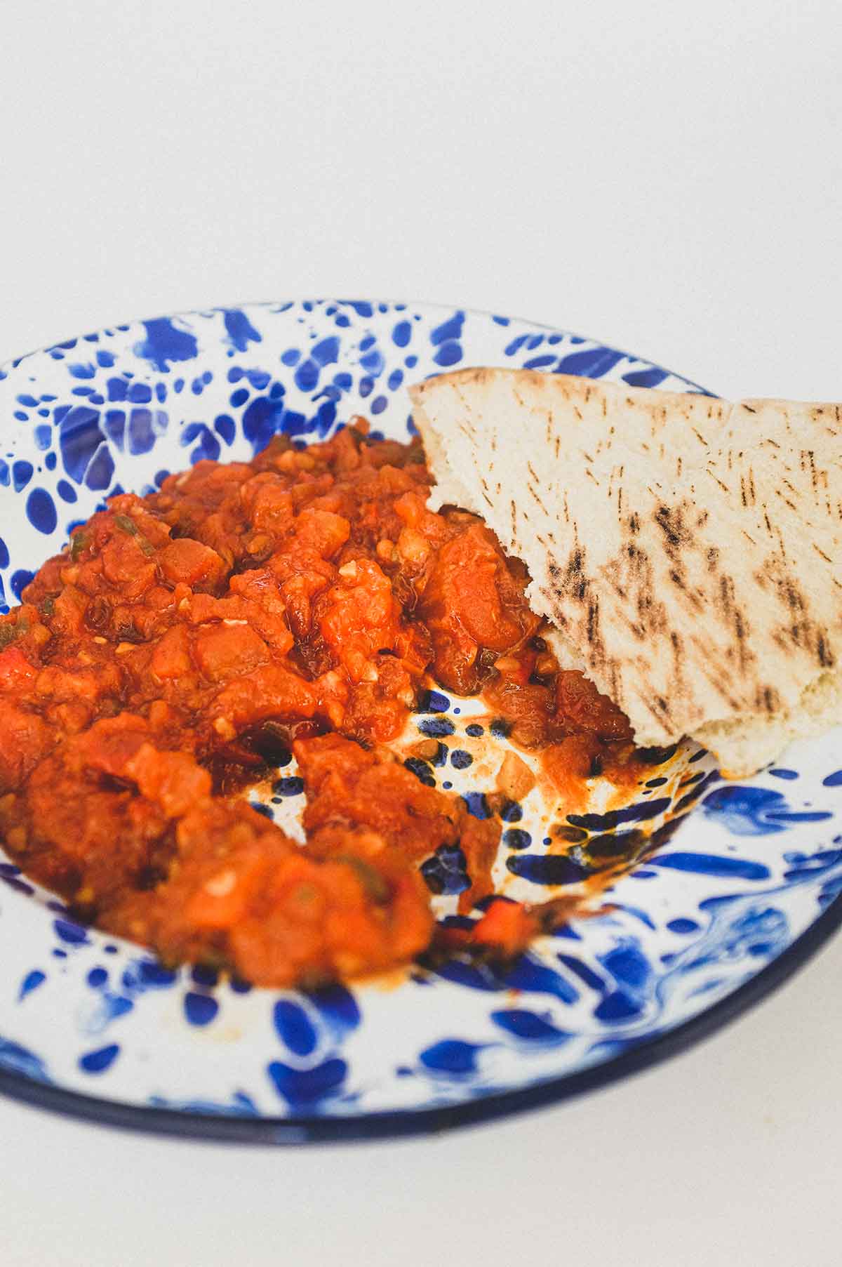 Moroccan Matbucha in a vibrant blue meze bowl. Peppers and tomatoes are stewed to a thick, tangy paste.