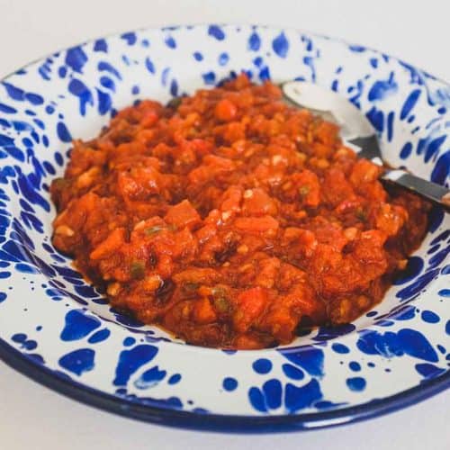 Moroccan Matbucha in a vibrant blue meze bowl. Peppers and tomatoes are stewed to a thick, tangy paste.