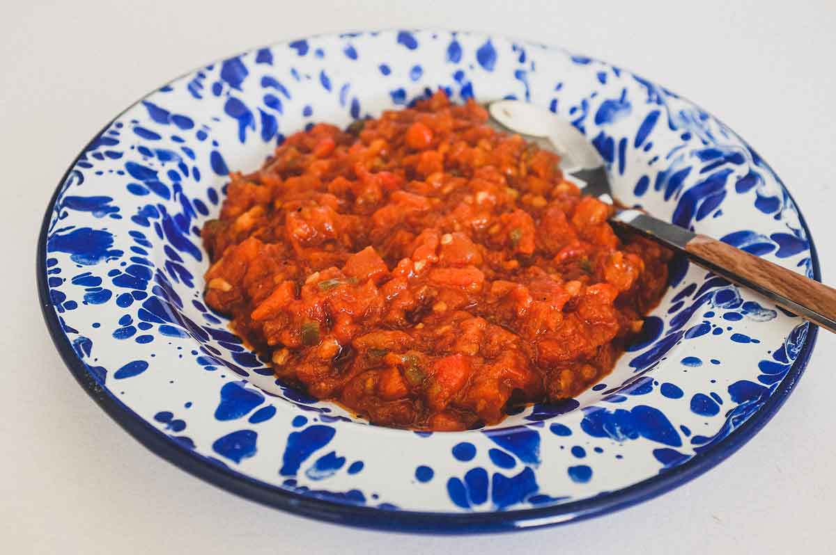 Moroccan Matbucha in a vibrant blue meze bowl. Peppers and tomatoes are stewed to a thick, tangy paste.