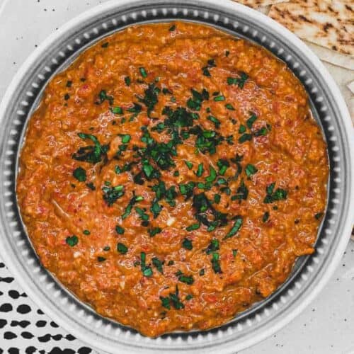 A bowl of Syrian Muhammara red pepper dip with flatbreads
