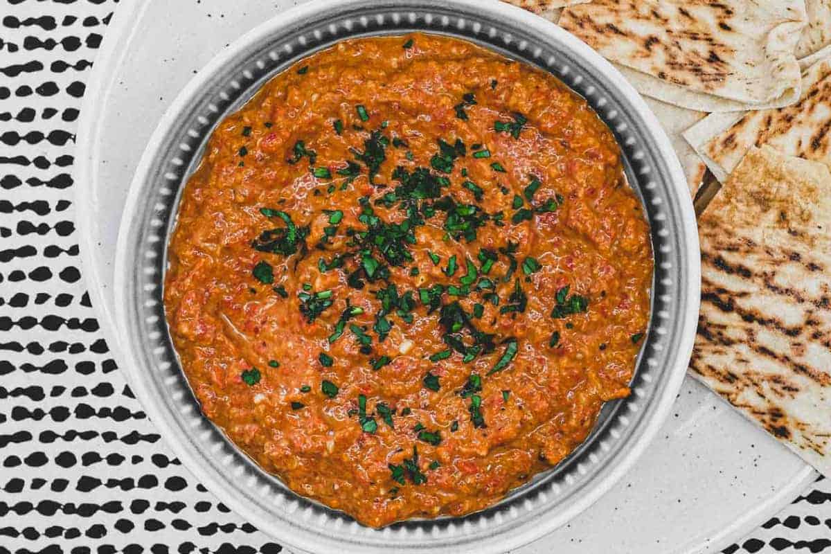 A bowl of Syrian Muhammara red pepper dip with flatbreads