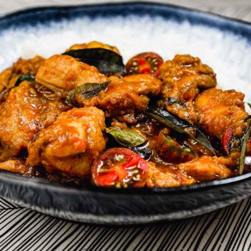 A bowl of chicken chukka curry with rice.