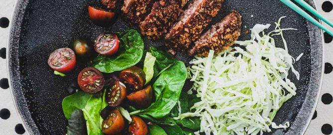 Menchi katsu and a small salad with shredded cabbage sit on a plate