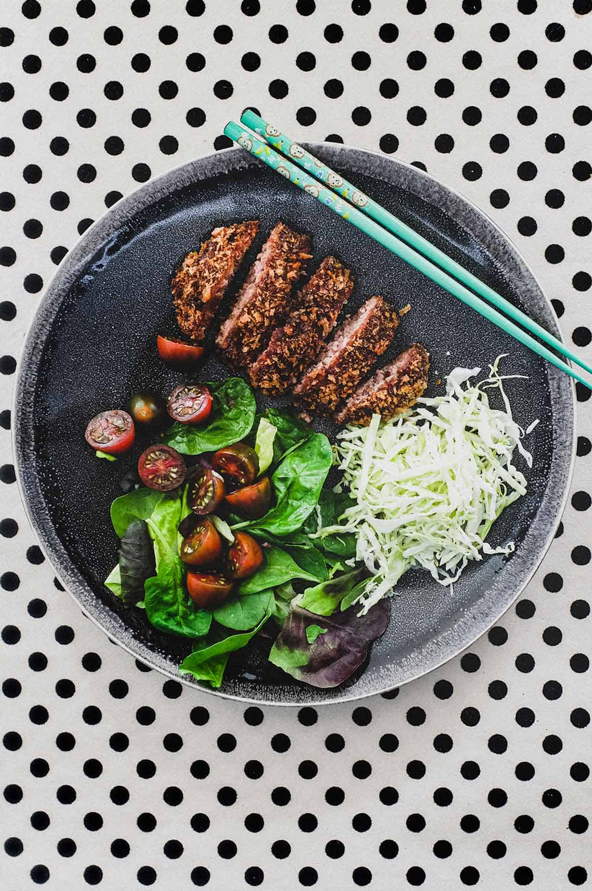 Menchi katsu and a small salad with shredded cabbage sit on a plate