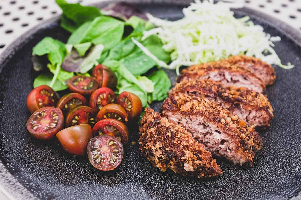 Menchi katsu and a small salad with shredded cabbage sit on a plate