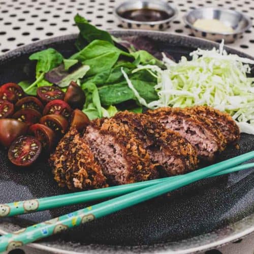Menchi katsu and a small salad with shredded cabbage sit on a plate