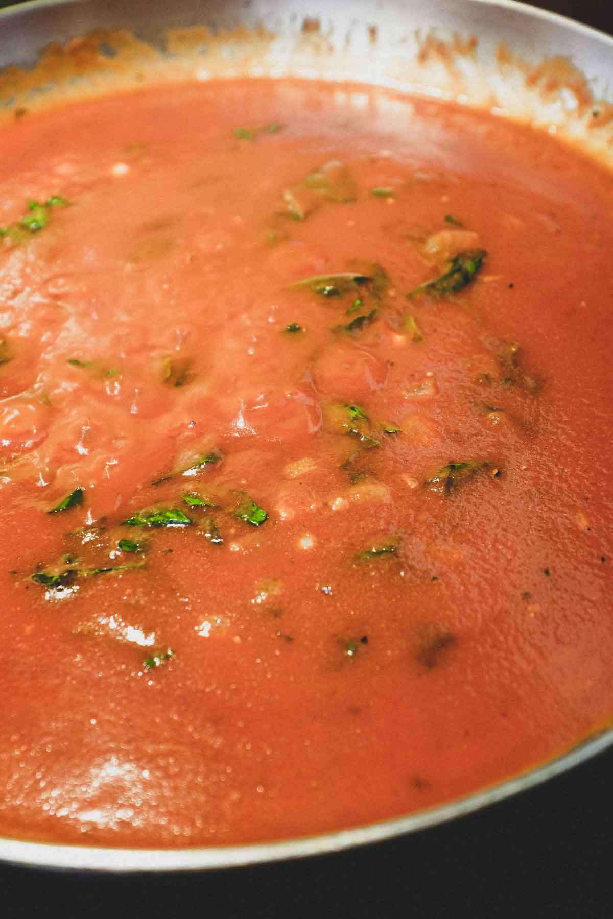 Tomato sauce with basil cooking in a pan