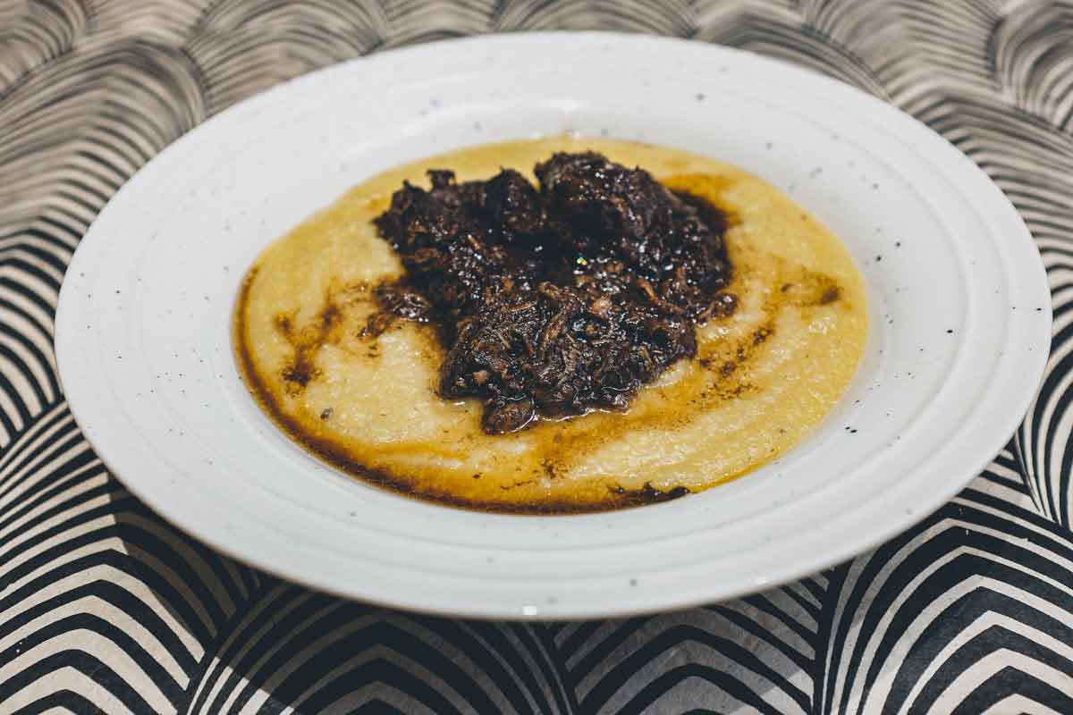 A bowl of Creamy Polenta with Peposo Alla Fornacina (Tuscan Beef Stew)