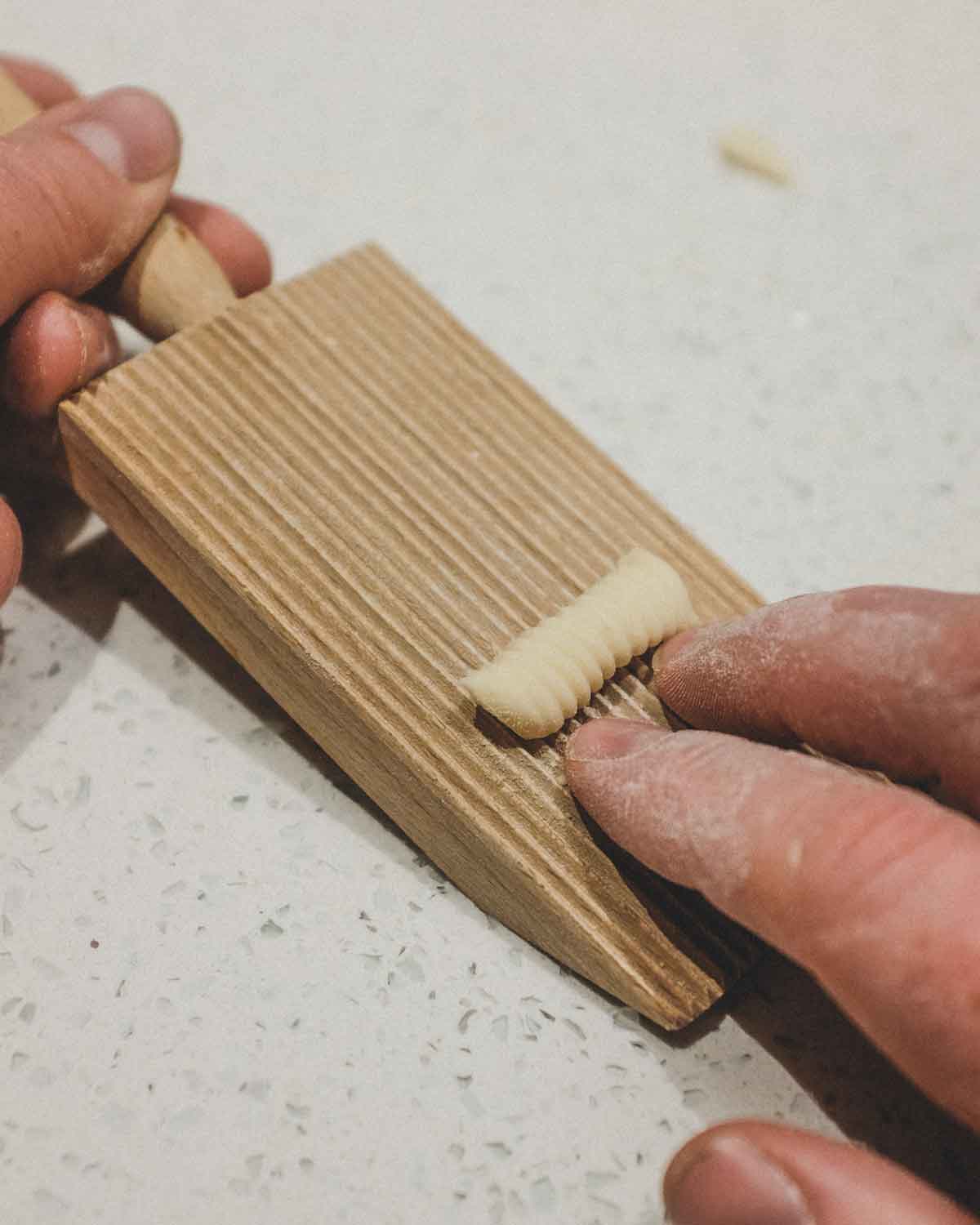 Rolling cavatelli pasta on a ridged gnocchi board