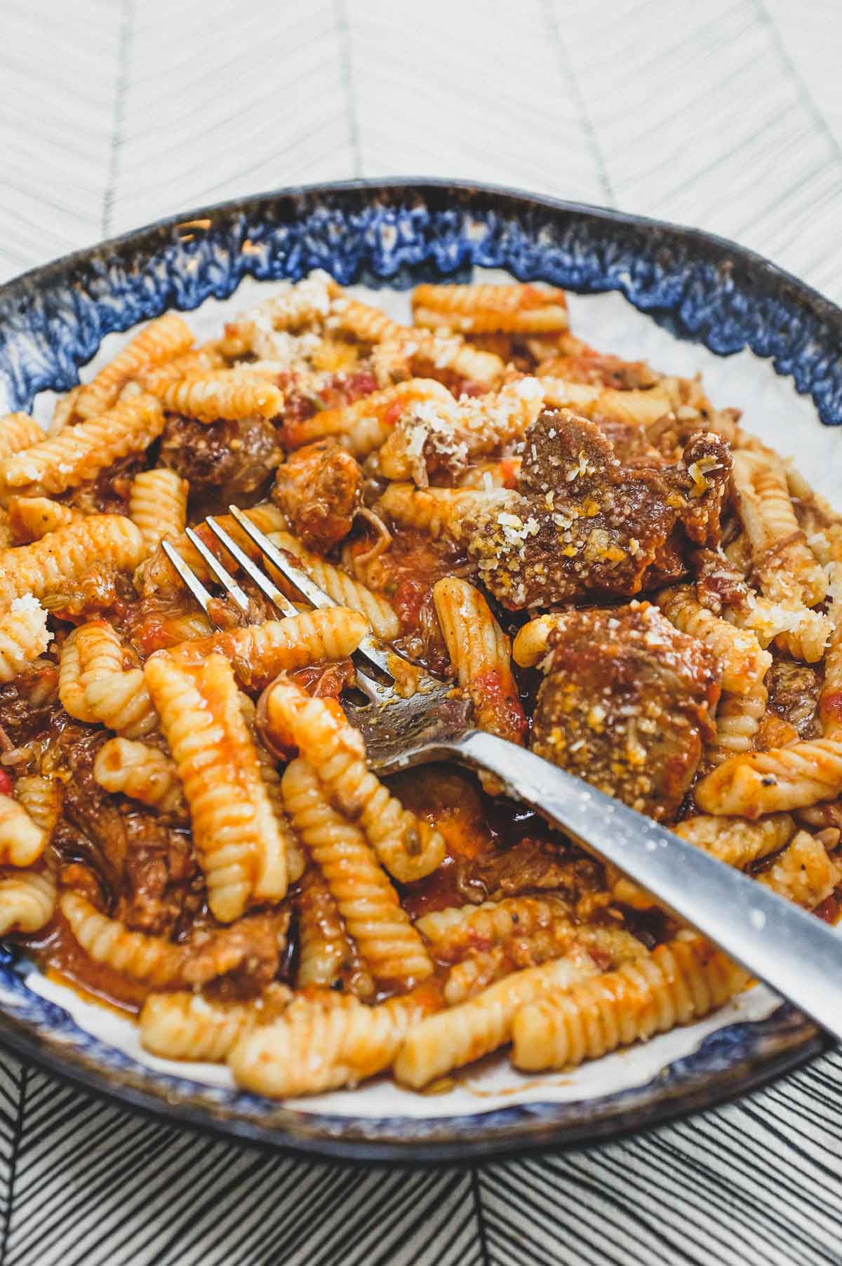 A bowl of cavatelli pasta with pork ragù with a fork