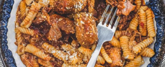 A bowl of cavatelli pasta with pork ragù with a fork