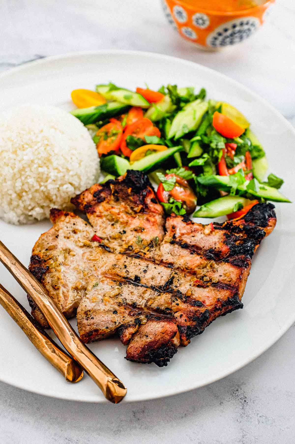 Pork chops marinated in lemongrass and other aromatic Vietnamese ingredients. Served with a simple salad of cucumber, tomato and herbs. A Nước chấm dipping sauce accompanies.