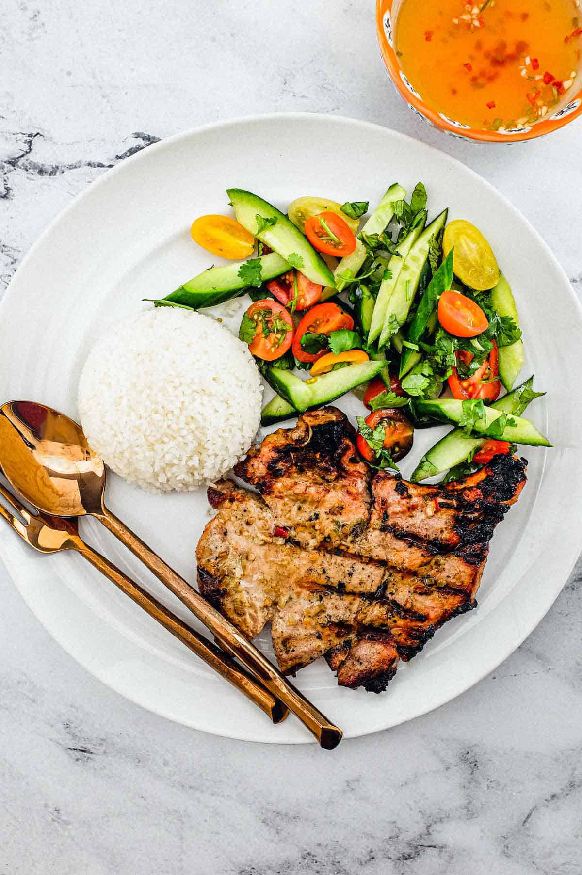 Pork chops marinated in lemongrass and other aromatic Vietnamese ingredients. Served with a simple salad of cucumber, tomato and herbs. A Nước chấm dipping sauce accompanies.