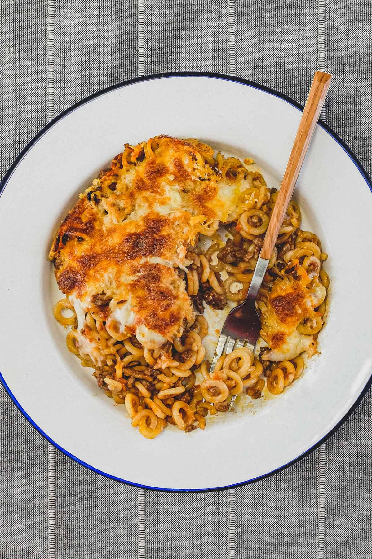 Anelletti Al Forno - baked rings of pasta in a tomato sauce in a bowl with a fork