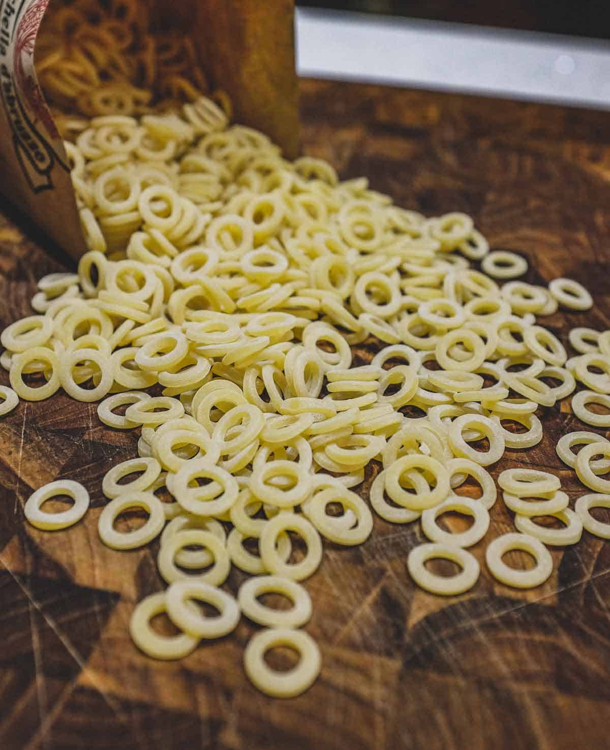 Dried pasta rings called Anelletti on a wooden board.