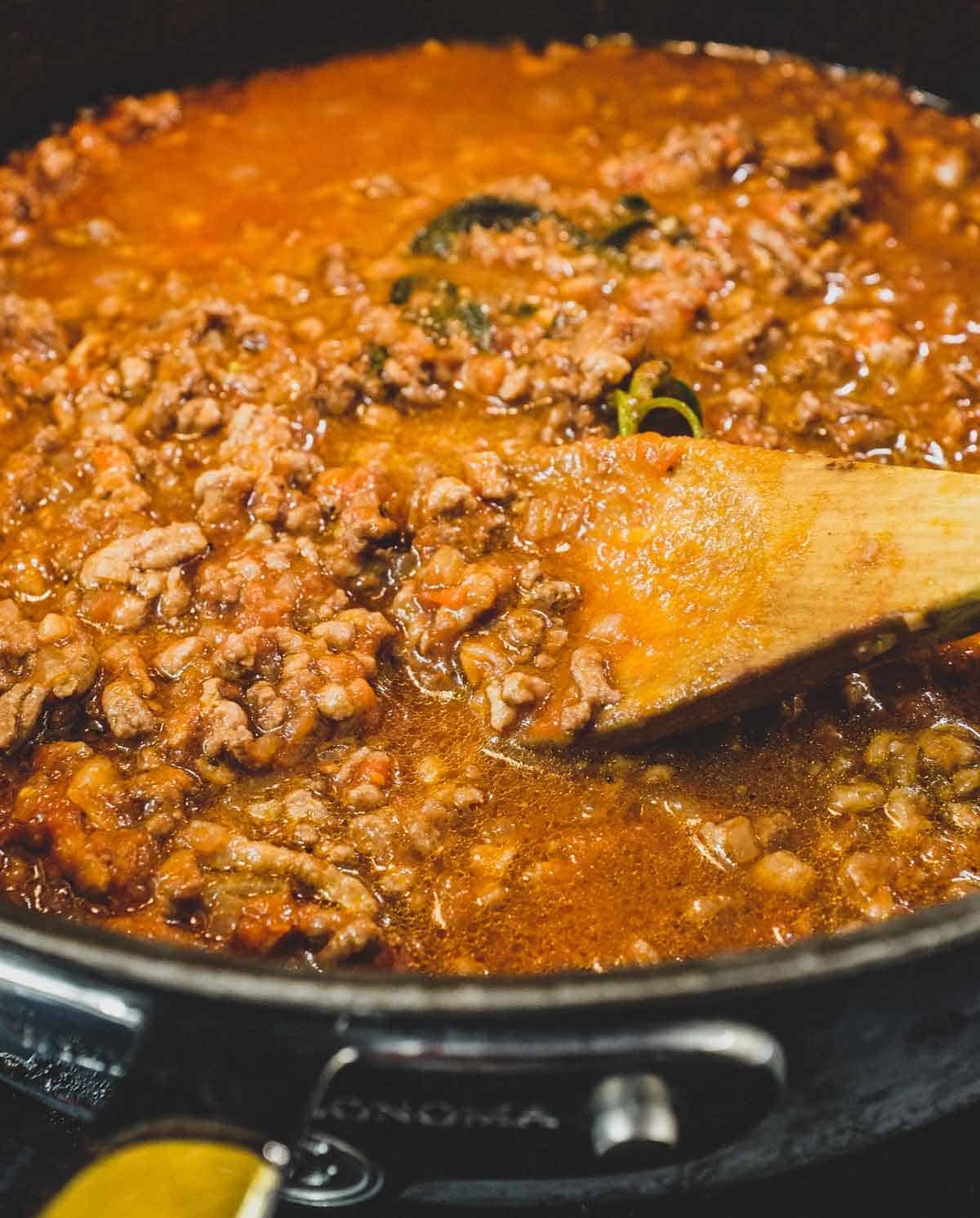 Stirring the meat sauce in a pan for the Anelletti al forno baked pasta.