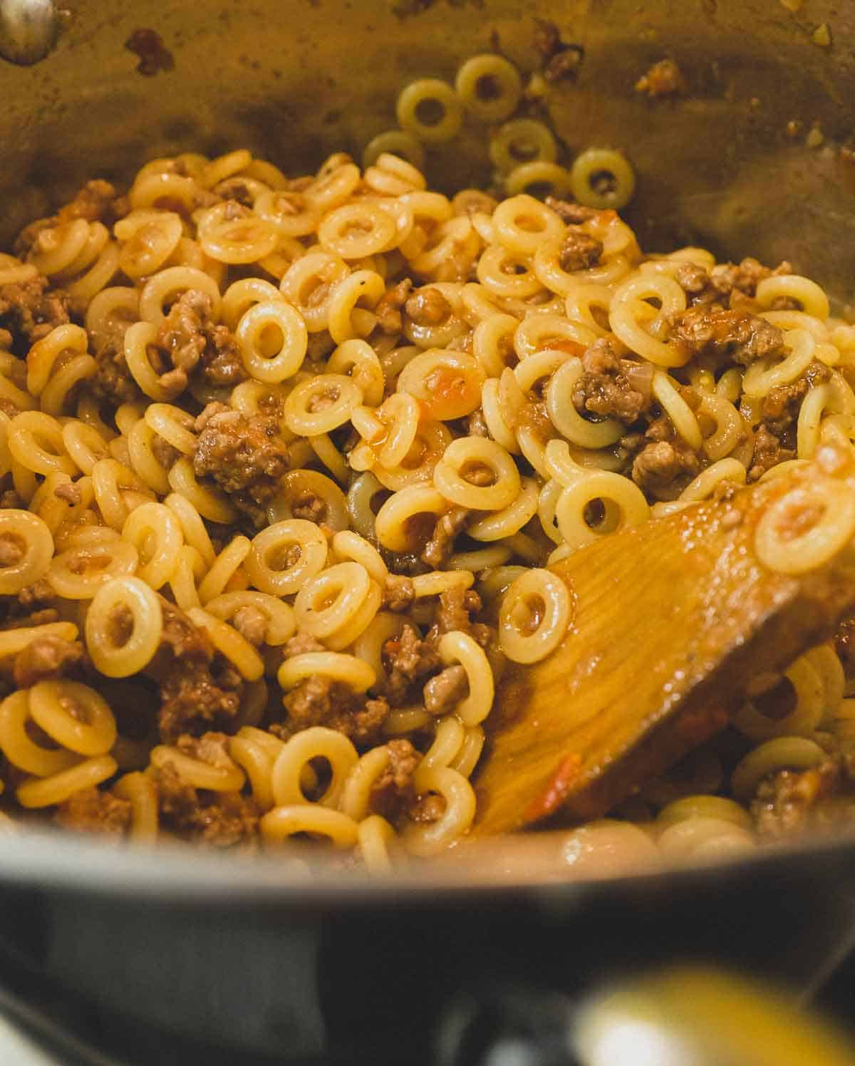 Stirring the anelletti into the meat sauce. 