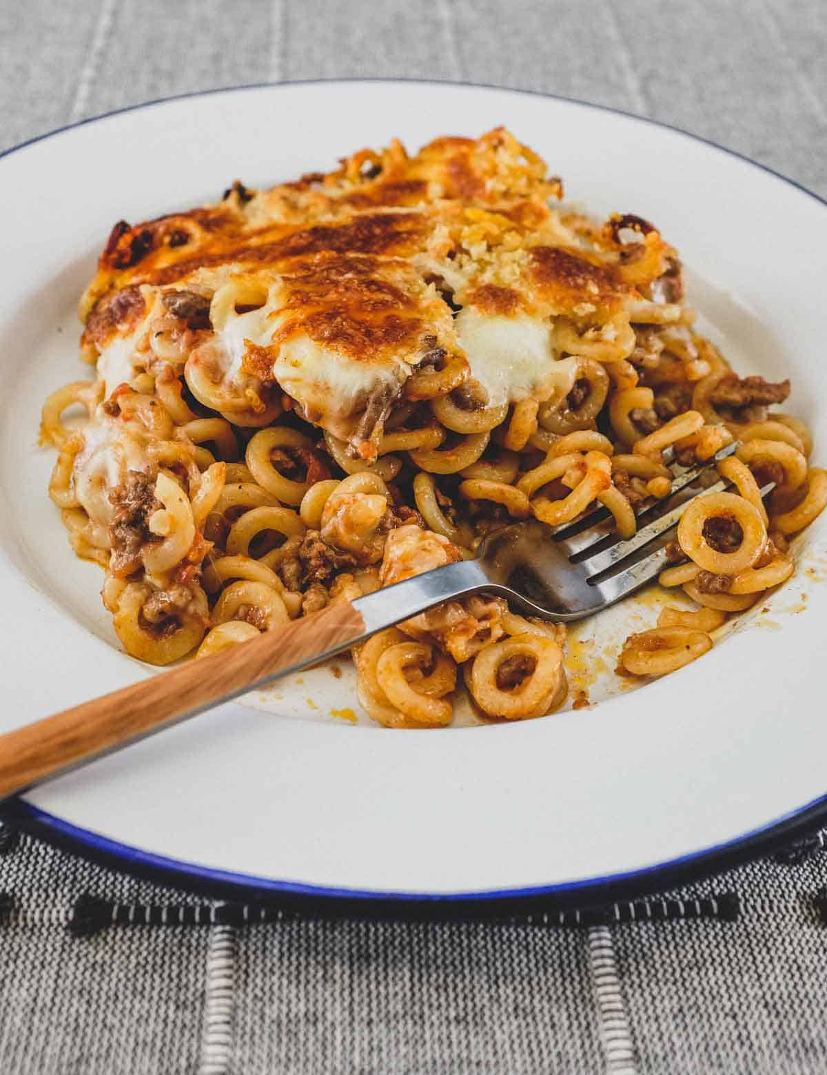 Anelletti Al Forno - baked rings of pasta in a tomato sauce in a bowl with a fork