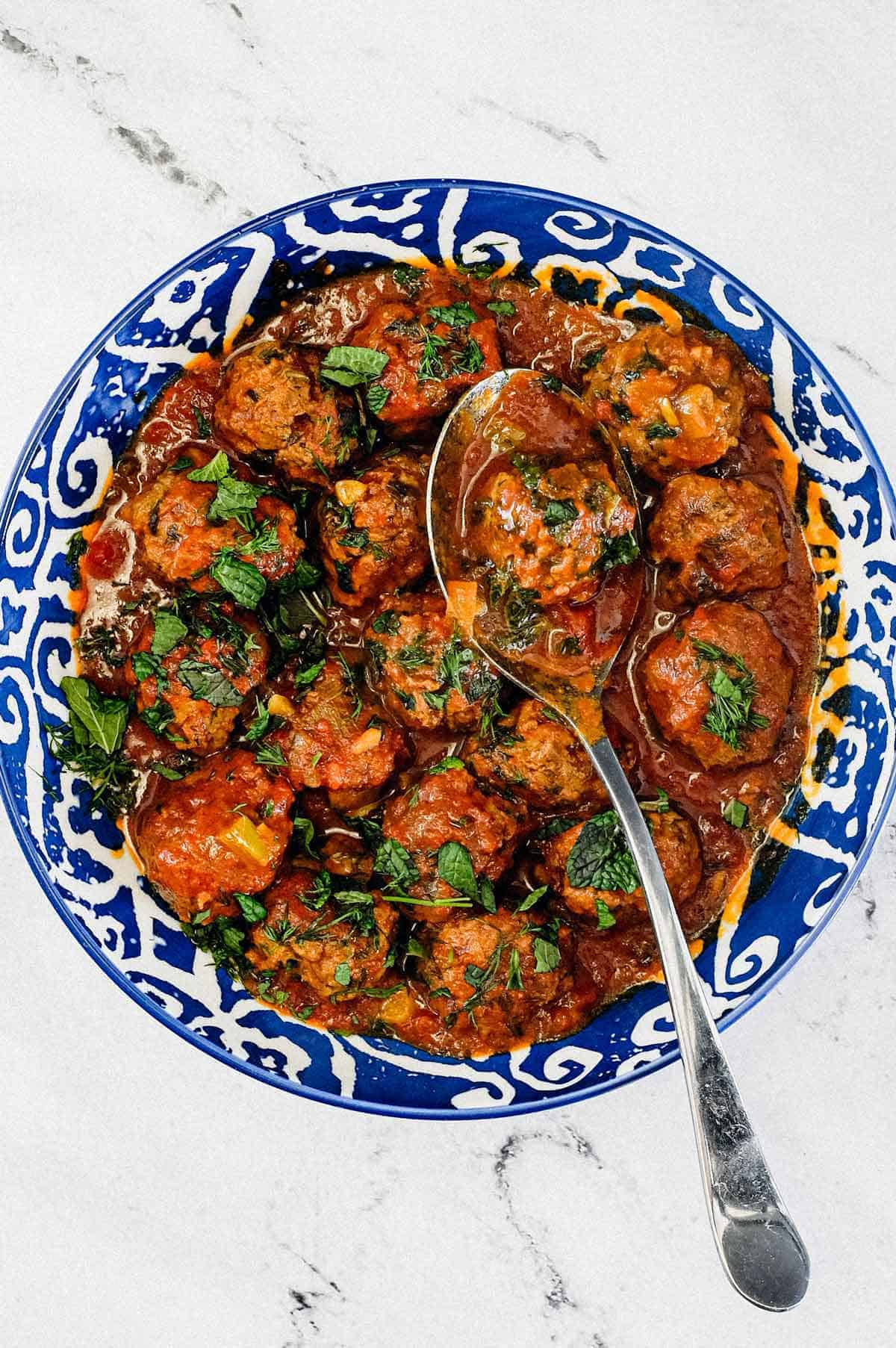 A large bowl of Moroccan Kefta (meatballs) tagine with a spoon.