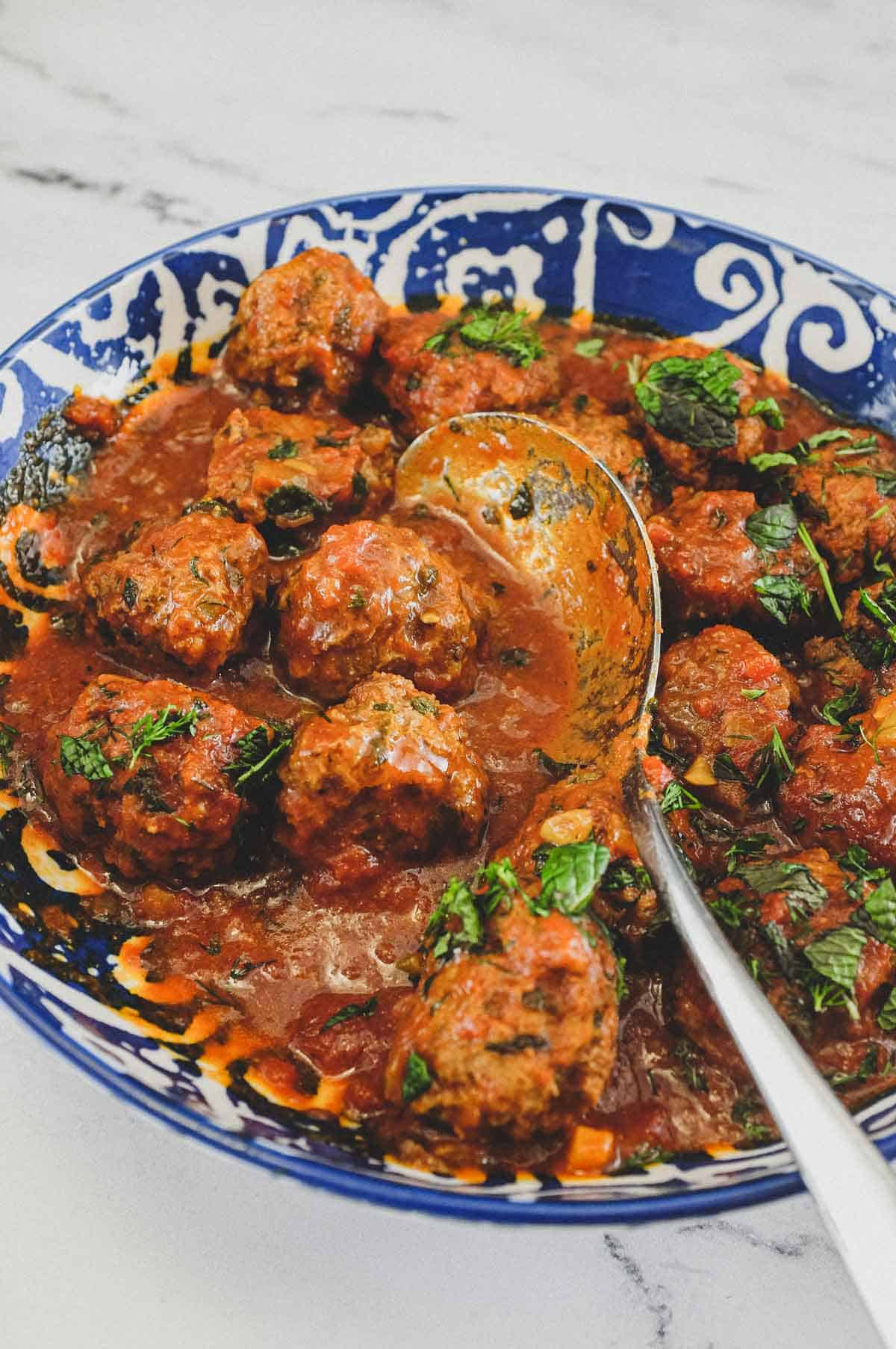 A large bowl of Moroccan Kefta (meatballs) tagine with a spoon.