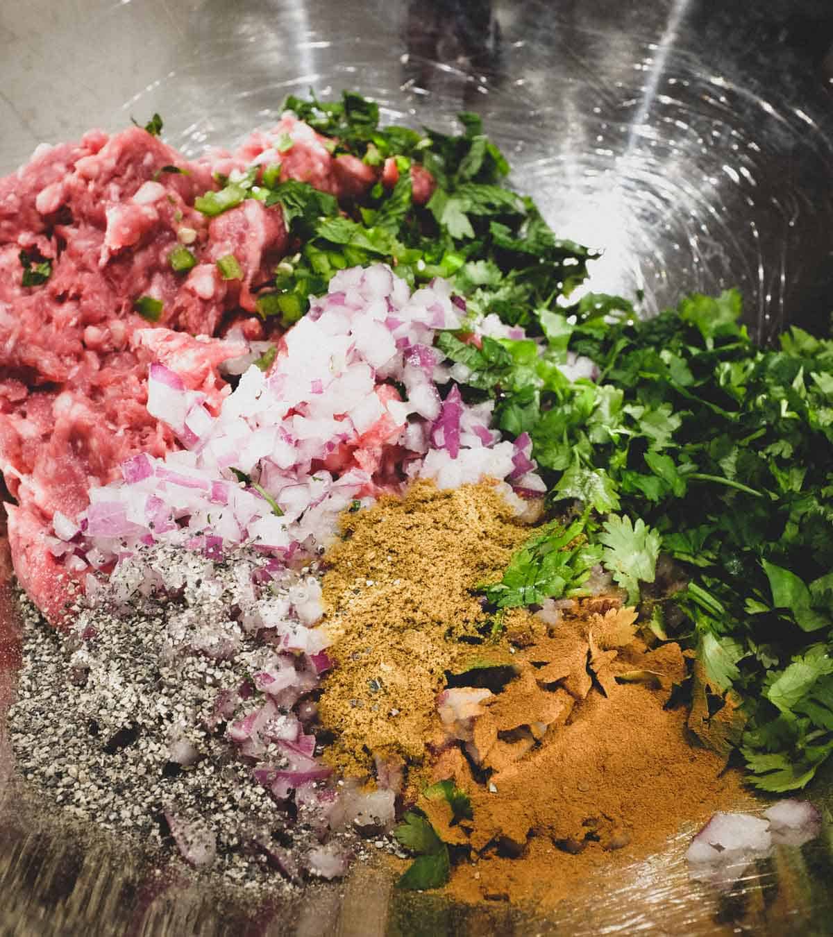 The ingredients for the Moroccan kefta (meatballs) in a large bowl. Minced lamb, spices and aromatics.