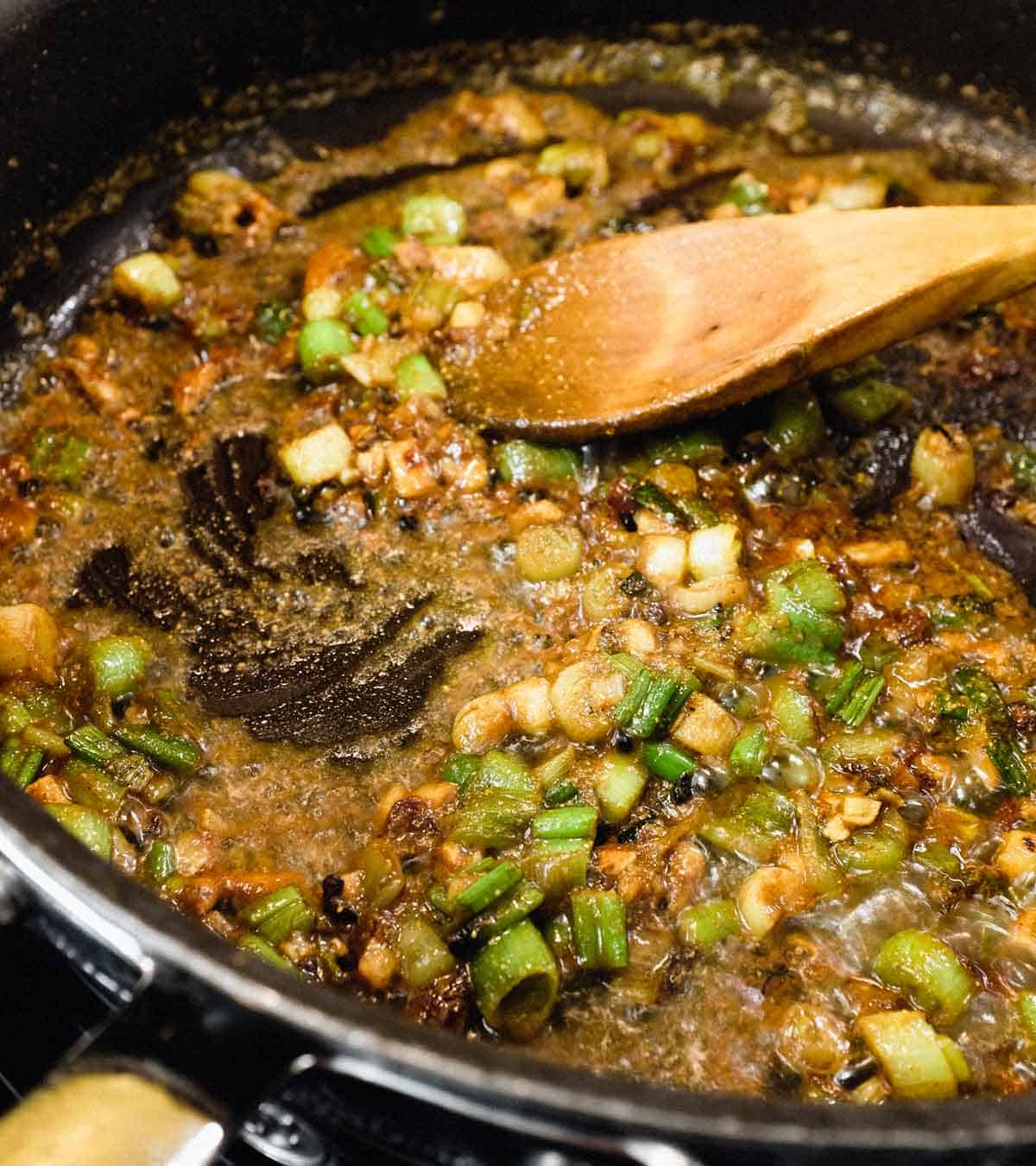 Onions and spices frying in a large deep pan.