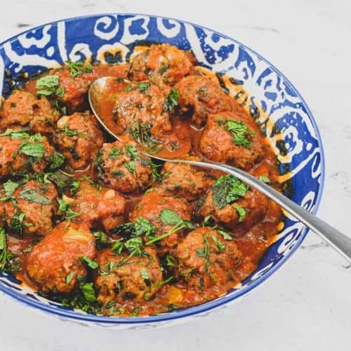 A large bowl of Moroccan Kefta (meatballs) tagine with a spoon.