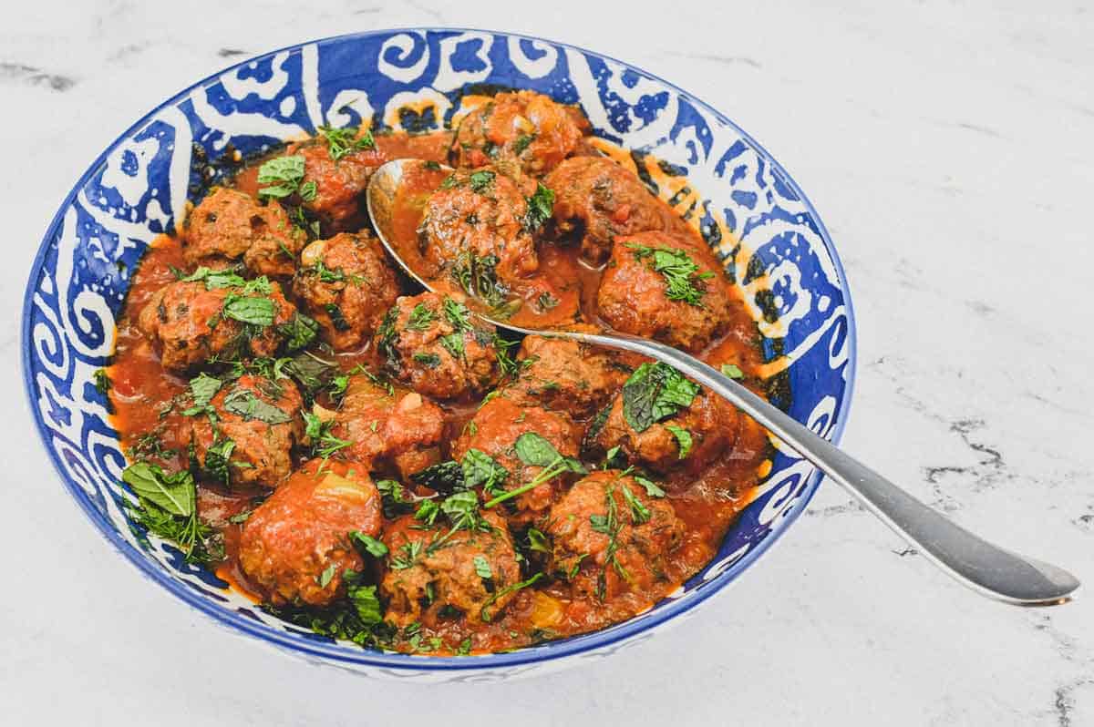 A large bowl of Moroccan Kefta (meatballs) tagine with a spoon.