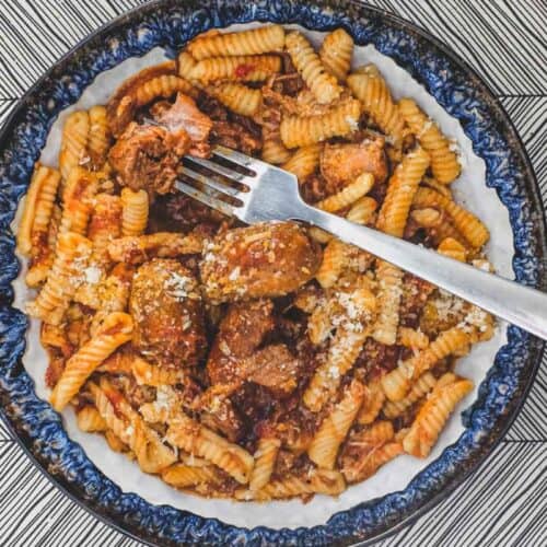 A bowl of cavatelli pasta with pork ragù with a fork
