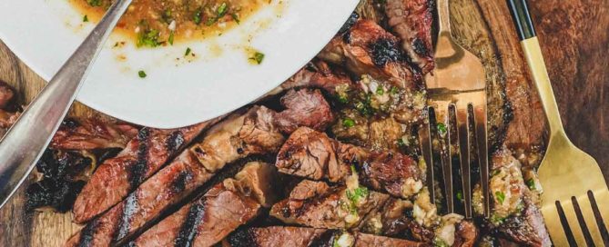 a wooden board with Thai Crying Tiger Beef with Nam Jim Jaew Sauce