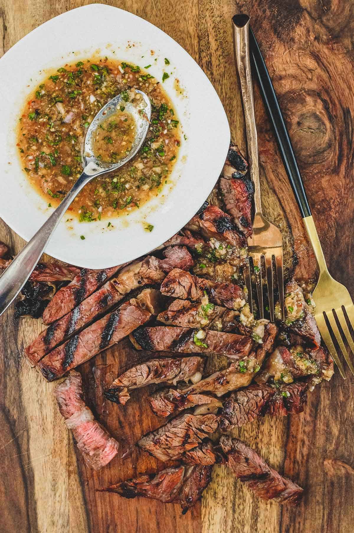 a wooden board with Thai Crying Tiger Beef with Nam Jim Jaew Sauce