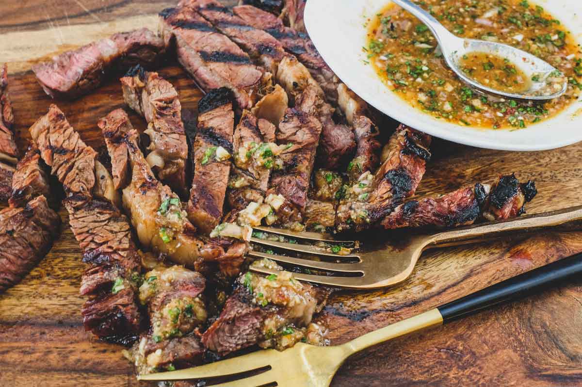 a wooden board with Thai Crying Tiger Beef with Nam Jim Jaew Sauce