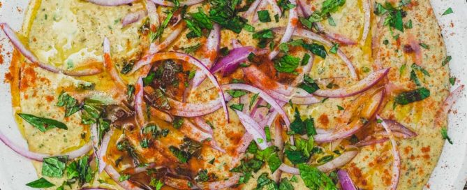 A bowl of Bessara scattered with vegetables, herbs and more