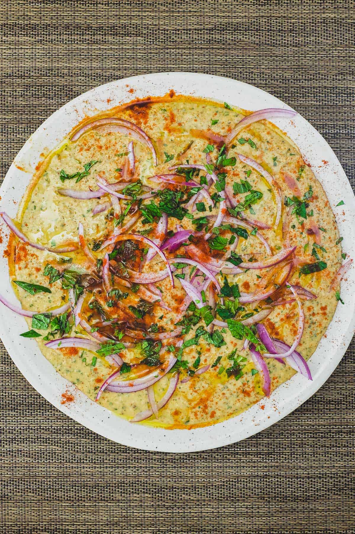 A bowl of Bessara scattered with vegetables, herbs and more