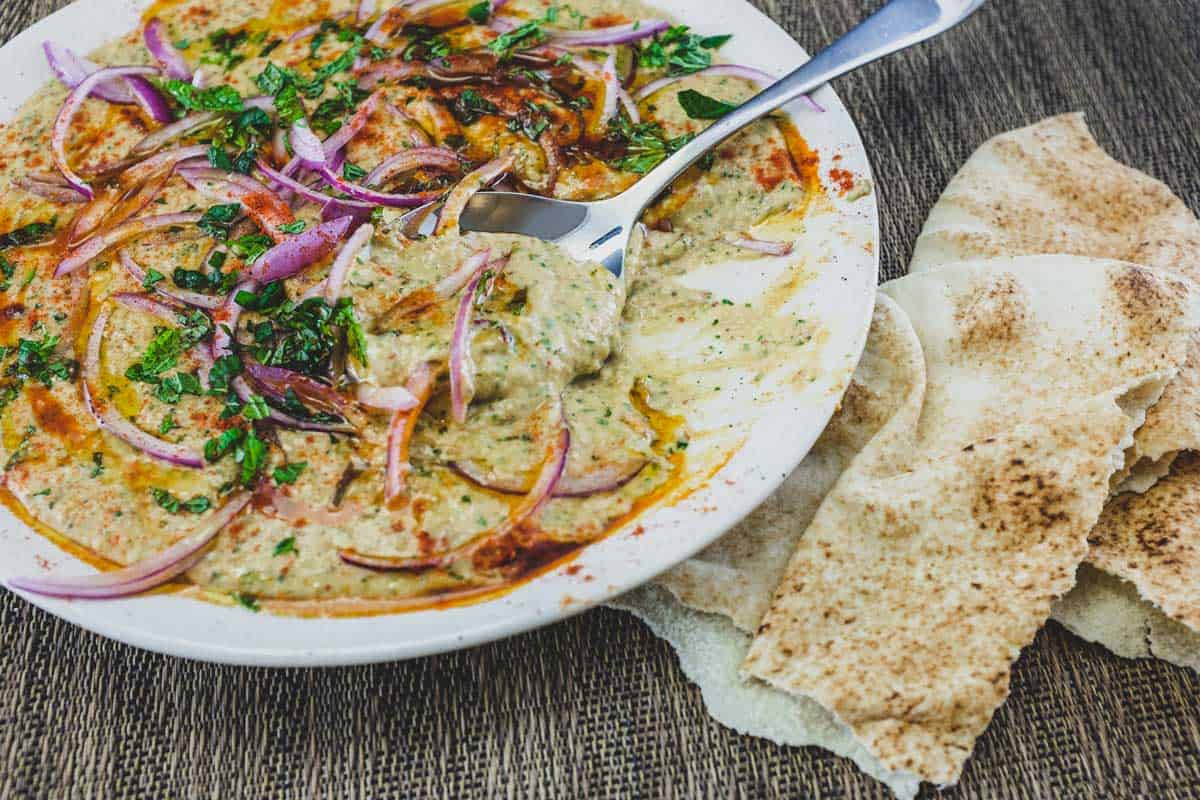 A bowl of Bessara scattered with vegetables, herbs and more