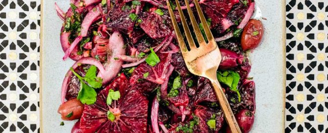 A platter of blood orange salad with black olives, onion and herbs