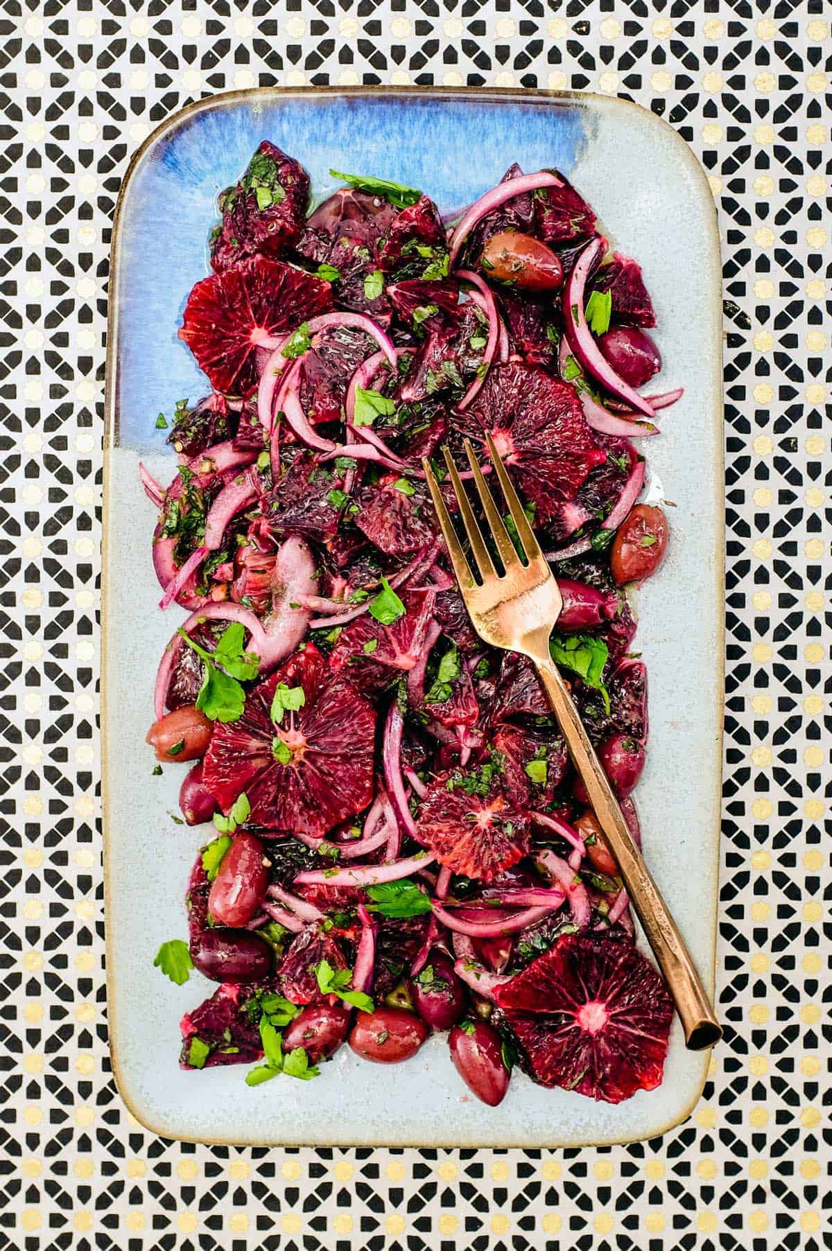 A platter of blood orange salad with black olives, onion and herbs