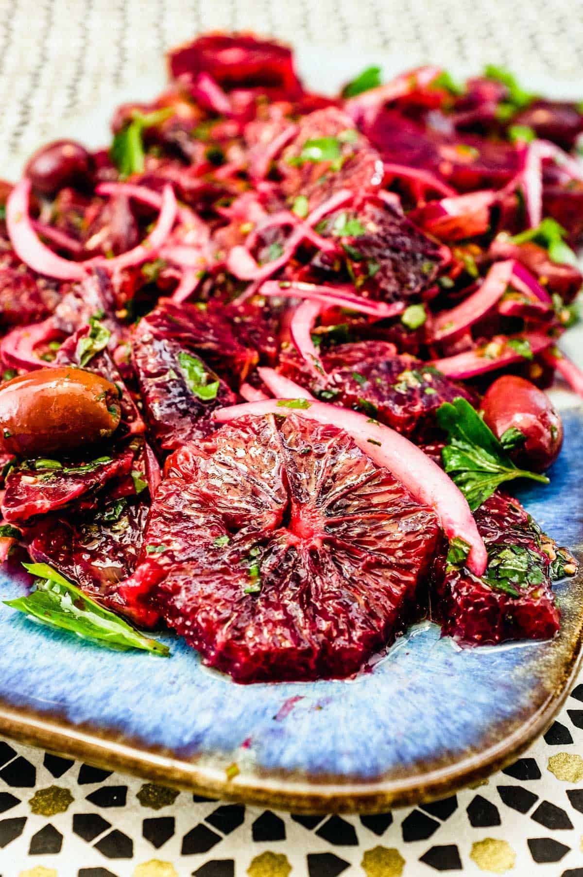 A platter of blood orange salad with black olives, onion and herbs