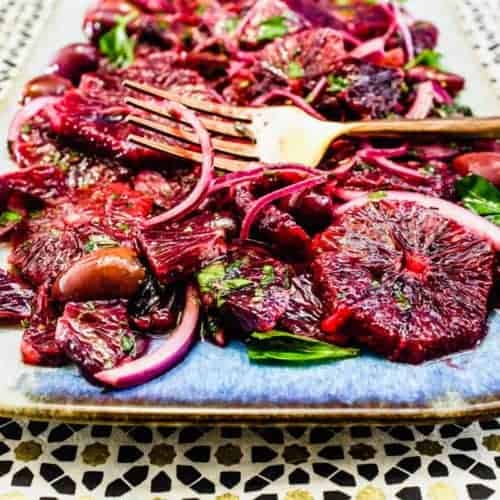 A platter of blood orange salad with black olives, onion and herbs