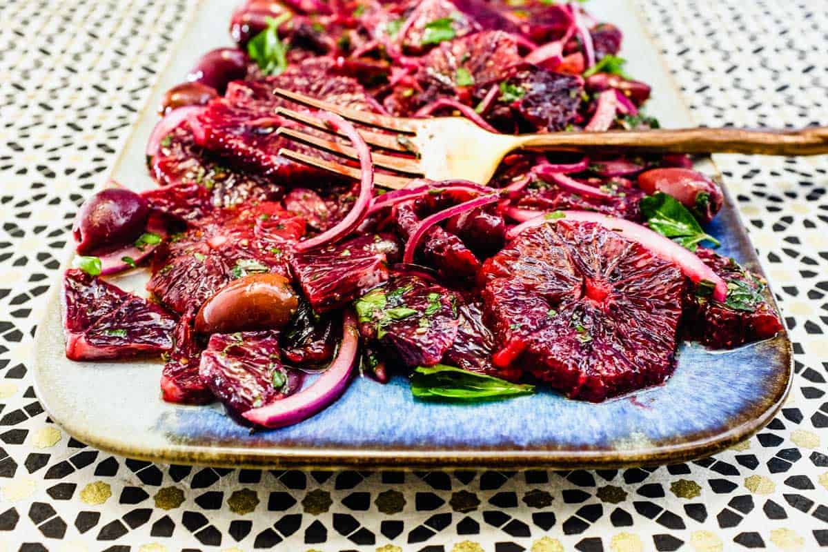 A platter of blood orange salad with black olives, onion and herbs