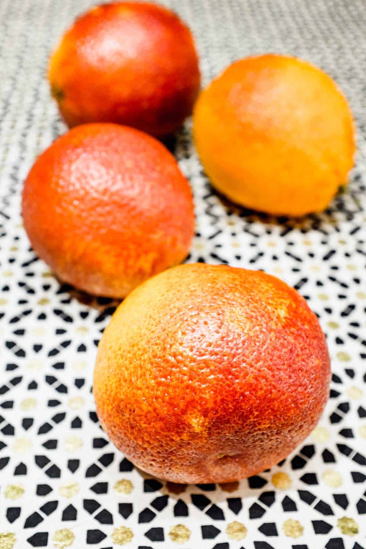 Three blood oranges on a patterned surface