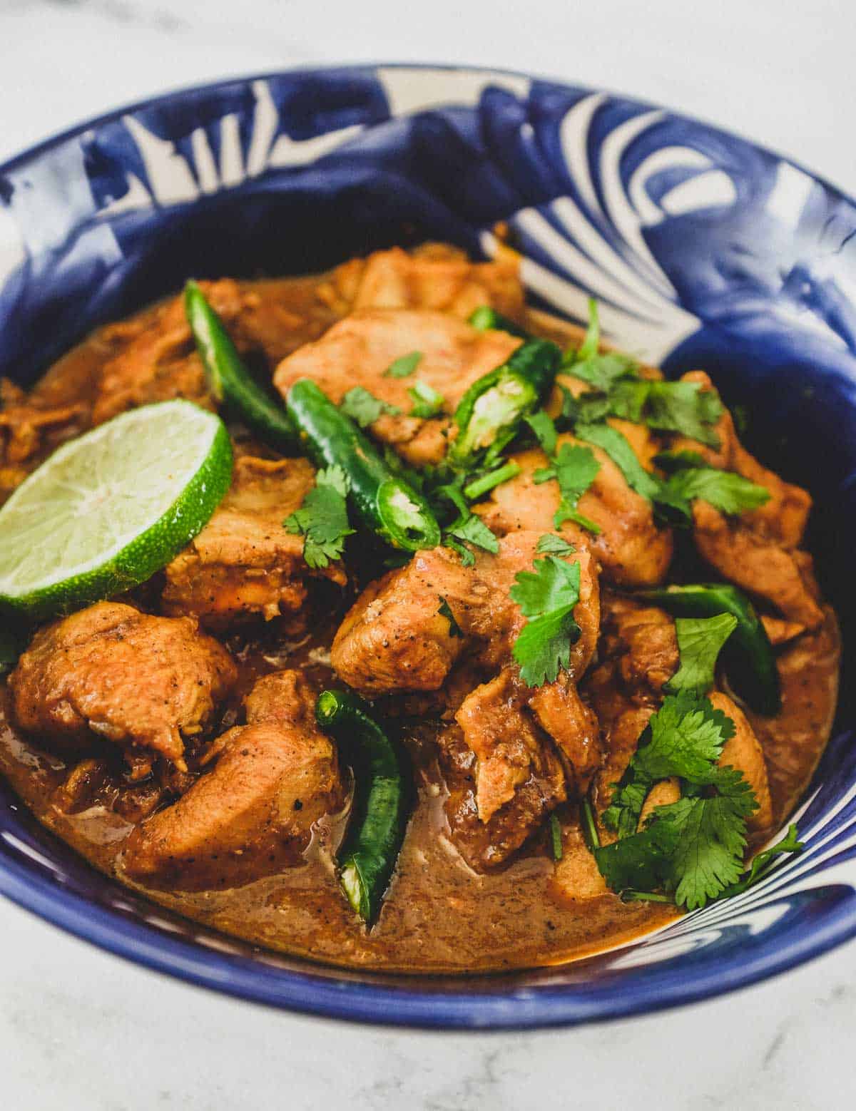 A blue bowl containing Keralan Chicken Curry (Nadan Khozi)