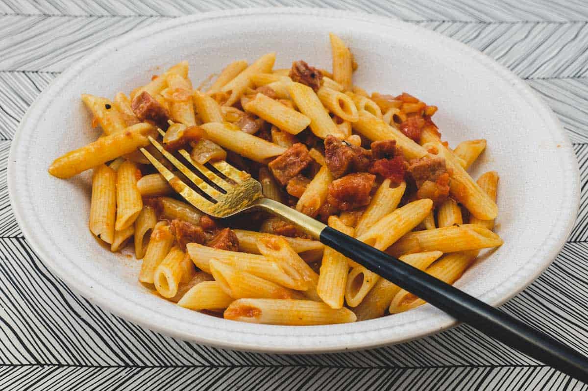 Penne pasta quills with tomato and salami sauce.